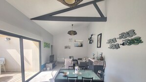 A modern living room with a glass dining table, a sofa, and a TV. - Renovated house with garden and terrace in La Chaume, near beach, WiFi (Les Sables-d'Olonne)