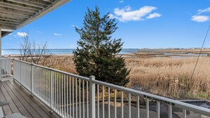 Un balcon donnant sur une plage et un arbre.