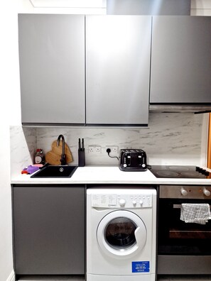 Enjoy cooking in this well-equipped kitchen with a washing machine, toaster, and sink.