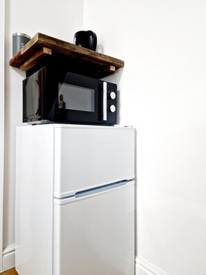 Kitchen essentials at your fingertips, featuring a refrigerator with microwave and a convenient coffee maker.