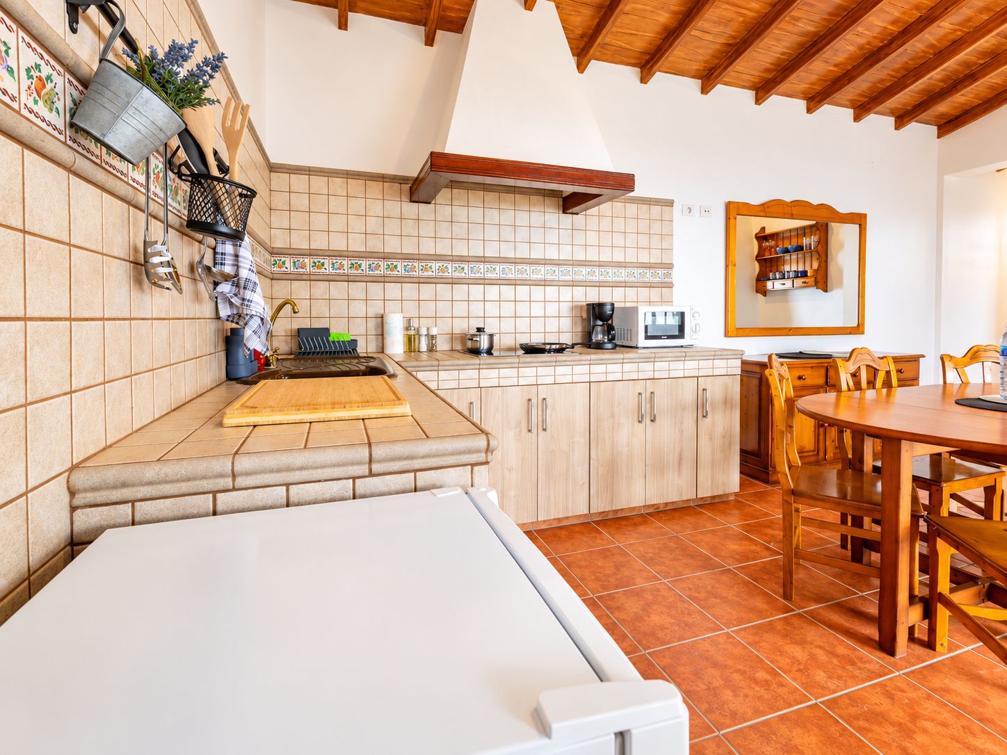 Una cocina con comedor, armarios de madera, un microondas y una cafetera.