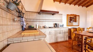 Una cocina con lavabo, estufa y armarios. Hay una mesa de comedor y sillas en la zona de comedor.