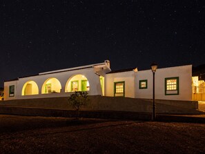 Un edificio con ventanas de arco y techo plano, bajo un cielo estrellado.