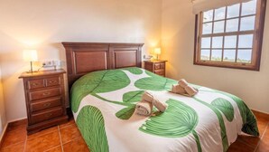 Un dormitorio con cama, dos mesitas de noche, una ventana y vistas al exterior.