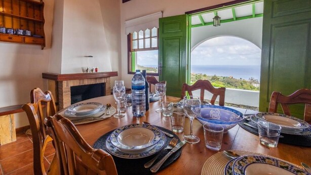 Una mesa de comedor dispuesta con platos, vasos y cubiertos, con vistas a un paisaje pintoresco.