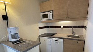 A compact kitchen with a coffee maker, microwave, dishwasher, and a small countertop. - 4-person apartment in Arzon, pool and parking, near beach and port (Arzon)