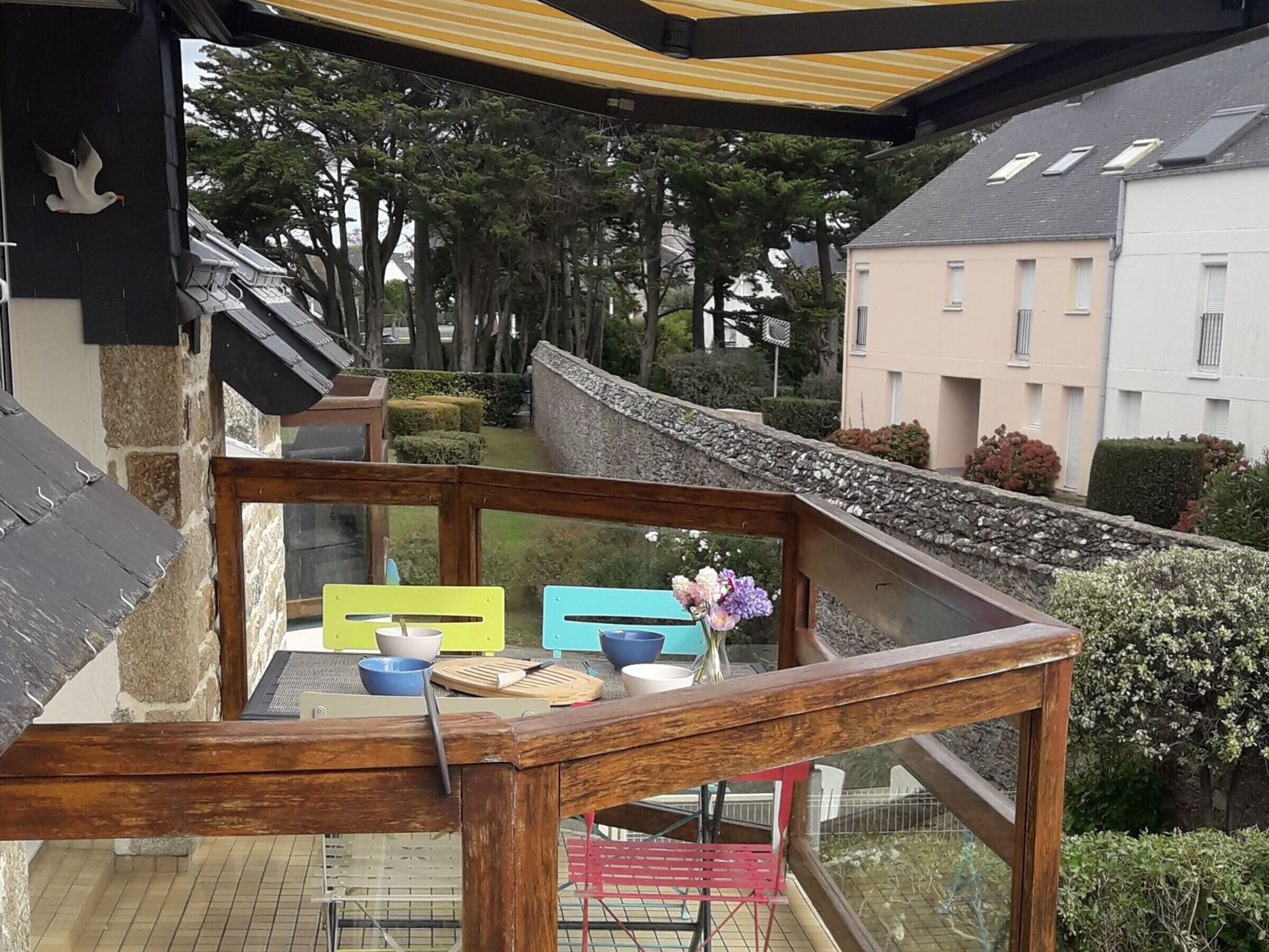 A wooden balcony with a view of a garden and buildings.