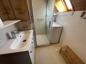 A compact bathroom with a shower, a sink, and a toilet.