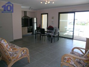 Relax in this spacious living area with a modern kitchen, dining table, and sliding glass door leading to an outdoor patio.