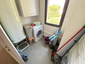 Convenient laundry facilities with a washing machine, drying rack, and storage for essentials.