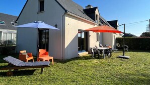 A house with a patio area featuring outdoor furniture and umbrellas. - Modern house 6 people, near Crouesty Port and beaches, Wi-Fi, garden, ideal for families (Arzon)