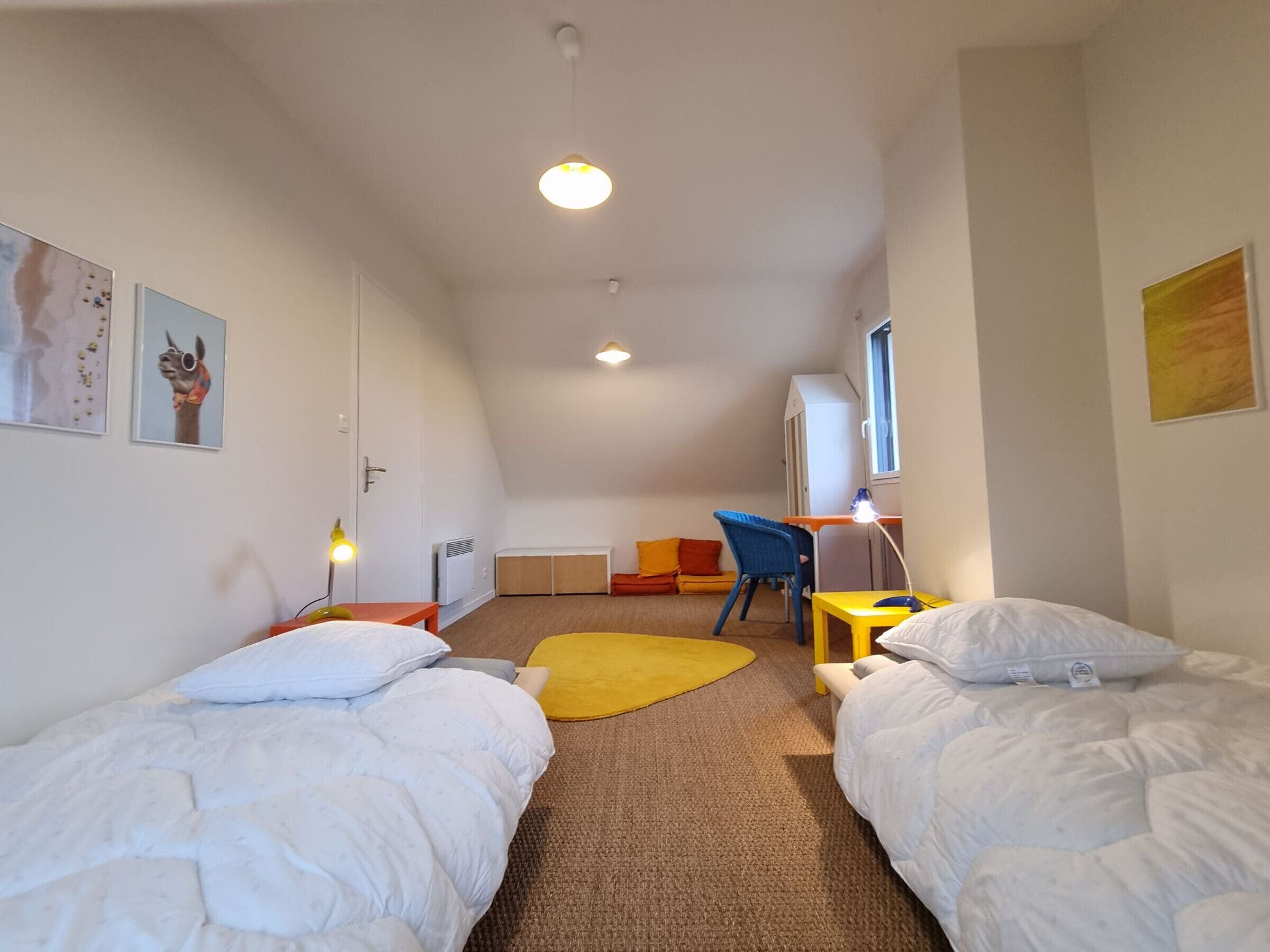 Een kamer met twee bedden, een bureau, een stoel, een radiator en een raam.