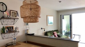 A modern kitchen with a wooden table, hanging wicker light fixture, and built-in shelves with various items.