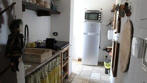 A kitchen with a white refrigerator, a microwave, and a sink. There are shelves above the counter holding dishes and a broom. - Nicolashouse on the sea 2 (Bari)