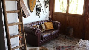 A room with a brown leather sofa, a wooden ladder, and a rustic decor including a wooden wall and a window with a view of bamboo. - Nicolashouse on the sea 2 (Bari)