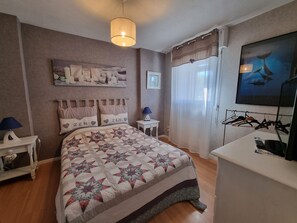 Makuuhuoneessa on sänky, yöpöydät, työpöytä, riippuvalaisin, taulu ja vaatekaappi.