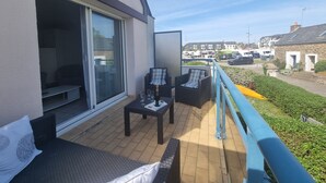A balcony with a sofa, chairs, and a table, overlooking a street with parked cars and buildings. - T3 Duplex Apartment, 4 Pers, Sarzeau Center, Balcony (Sarzeau)