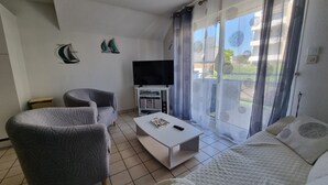 A living room with a sofa, armchair, coffee table, TV, and a balcony with curtains. - T3 Duplex Apartment, 4 Pers, Sarzeau Center, Balcony (Sarzeau)