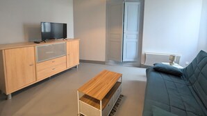 A living room with a wooden cabinet, a television, a sofa, and a ceiling light.