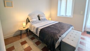 A bedroom with a bed, bedside tables, a window, and a bench.