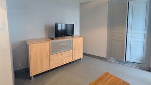 A room with a wooden cabinet, a television on top, and a door to the right.