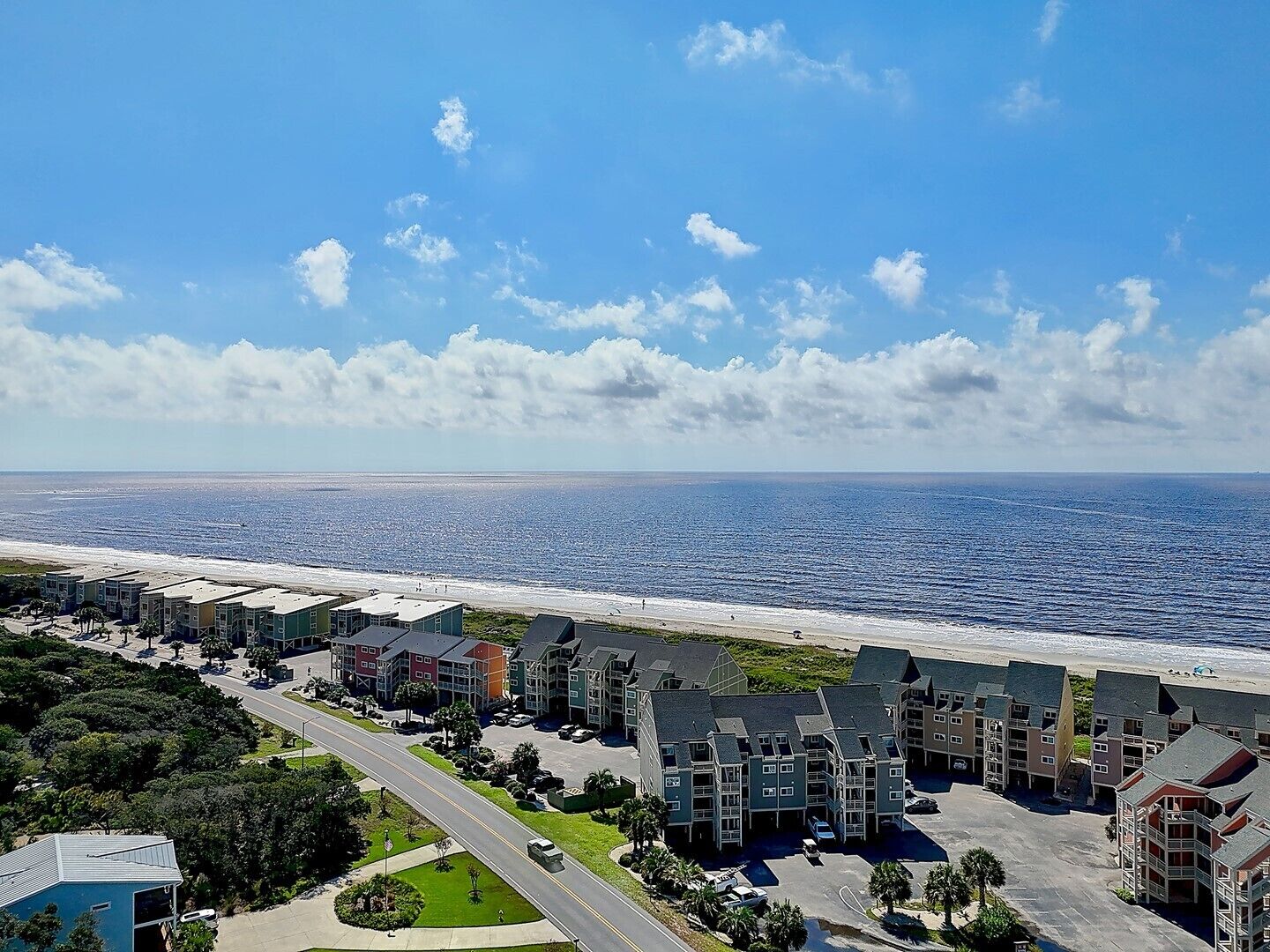 A coastal hotel with multiple buildings, a beach view, and a clear sky.