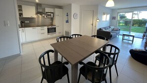 A modern kitchen with white cabinets and a dining area with a wooden table and black chairs.