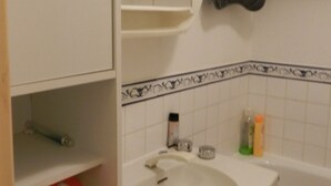 Uma casa de banho com uma pia branca, um espelho e um porta-toalhas.