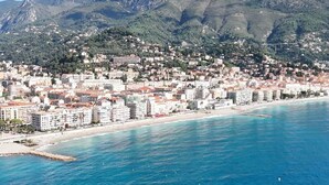 Une ville côtière avec une plage, des bâtiments et des montagnes en arrière-plan.