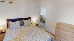 Une chambre à coucher comprenant un lit, des tables de chevet, une commode et un miroir.