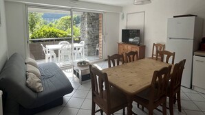 A compact living space with a dining area, sofa, TV, and a view of greenery through the sliding glass door. - Spacious well-equipped chalet with parking in Cauterets (Cauterets)