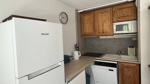 A compact kitchen with a white refrigerator, wooden cabinets, a microwave, a sink, and a clock on the wall. - Spacious well-equipped chalet with parking in Cauterets (Cauterets)