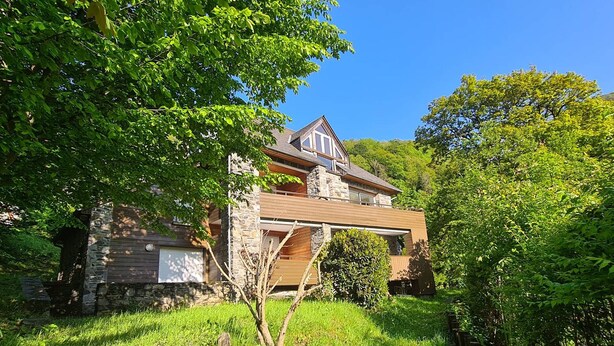 A two-story stone house with a wooden extension, surrounded by lush greenery and a small stream. - Spacious well-equipped chalet with parking in Cauterets (Cauterets)