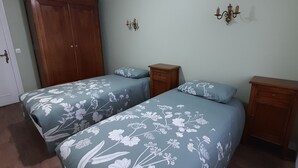 A bedroom with two beds, wooden wardrobes, and wall sconces. - Charming cottage with garden, WiFi, pets welcome (Thorigné-sur-Dué)