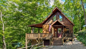 Une cabane en bois avec un porche, un drapeau et un chemin de gravier.