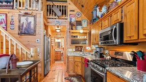 L’intérieur d’un chalet rustique est doté de murs en bois, d’un coin cuisine comprenant une cuisinière, un four à micro-ondes et un réfrigérateur, ainsi que d’un coin repas avec un banc et une table.