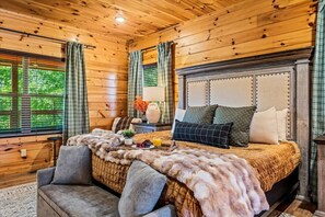 Un dormitorio rústico de cabaña de troncos con una cama grande, un sofá y una mesita de noche.