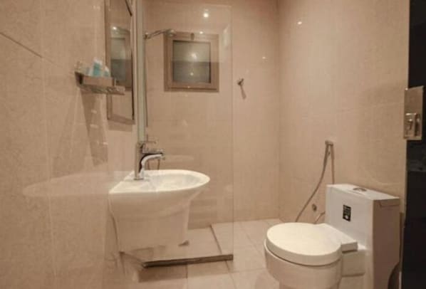 A bathroom with a pedestal sink, a toilet, and a shower area. - Darina Serviced Apartments (Riyadh)