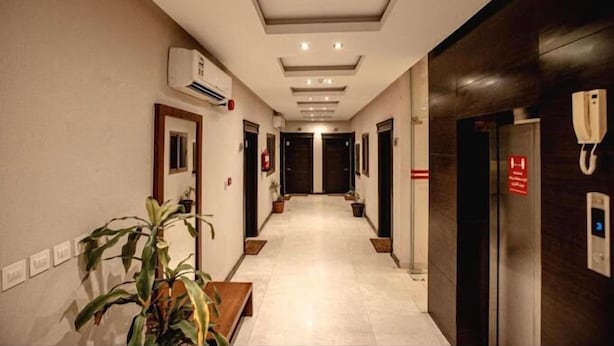 Ein Hotelkorridor im modernen Design, mit einer langen Diele, an beiden Seiten Türen, einer Klimaanlage links und einem Aufzug rechts.