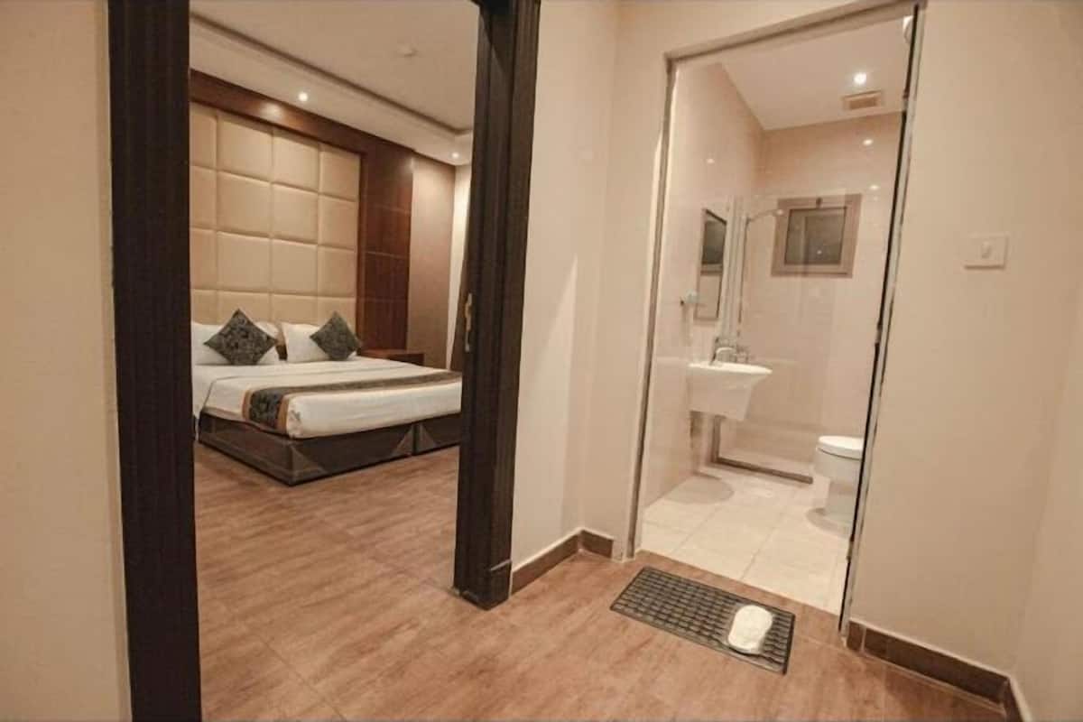 A bedroom with a bed, a bathroom with a toilet and sink, and a shower area.