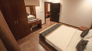 Ein Schlafzimmer mit einem Bett, einem Schminktisch, einem Spiegel und einer Tür zu einem weiteren Raum.