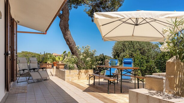 Un patio con mobiliario exterior, una mesa y una sombrilla grande.