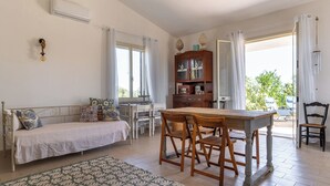 Una habitación con cama, una mesa de madera con sillas, un armario y vistas al exterior.