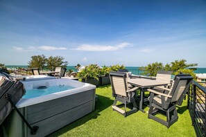 A rooftop terrace with a hot tub, outdoor furniture, and a view of the ocean. - Gulfside Sunset - 2309A   “Anna Maria Island” (Bradenton Beach)