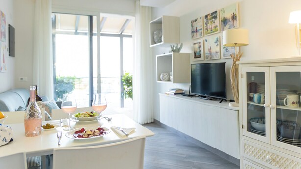 A modern kitchen with a dining area, large windows, and a TV. - Perla Abernathy - vacation home by the sea with pool and garden (Boissano)