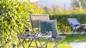 A garden setting with a metal table and two chairs, one with a cushion. - Perla Abernathy - vacation home by the sea with pool and garden (Boissano)