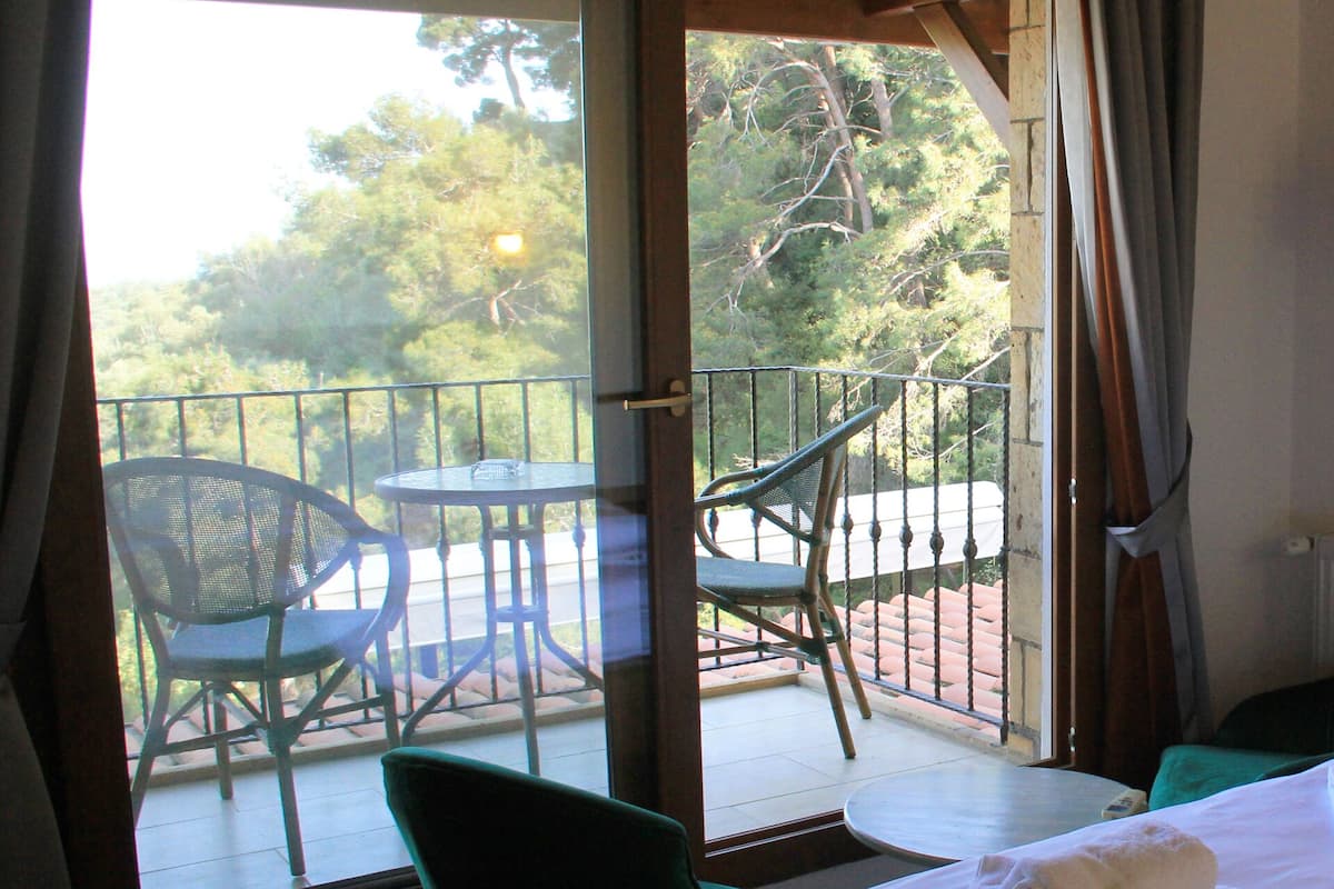 Varanda com duas cadeiras e uma mesa, com vista para uma área arborizada.