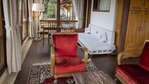 Una stanza accogliente con una poltrona in velluto rosso, un tavolo di legno e un divano bianco.