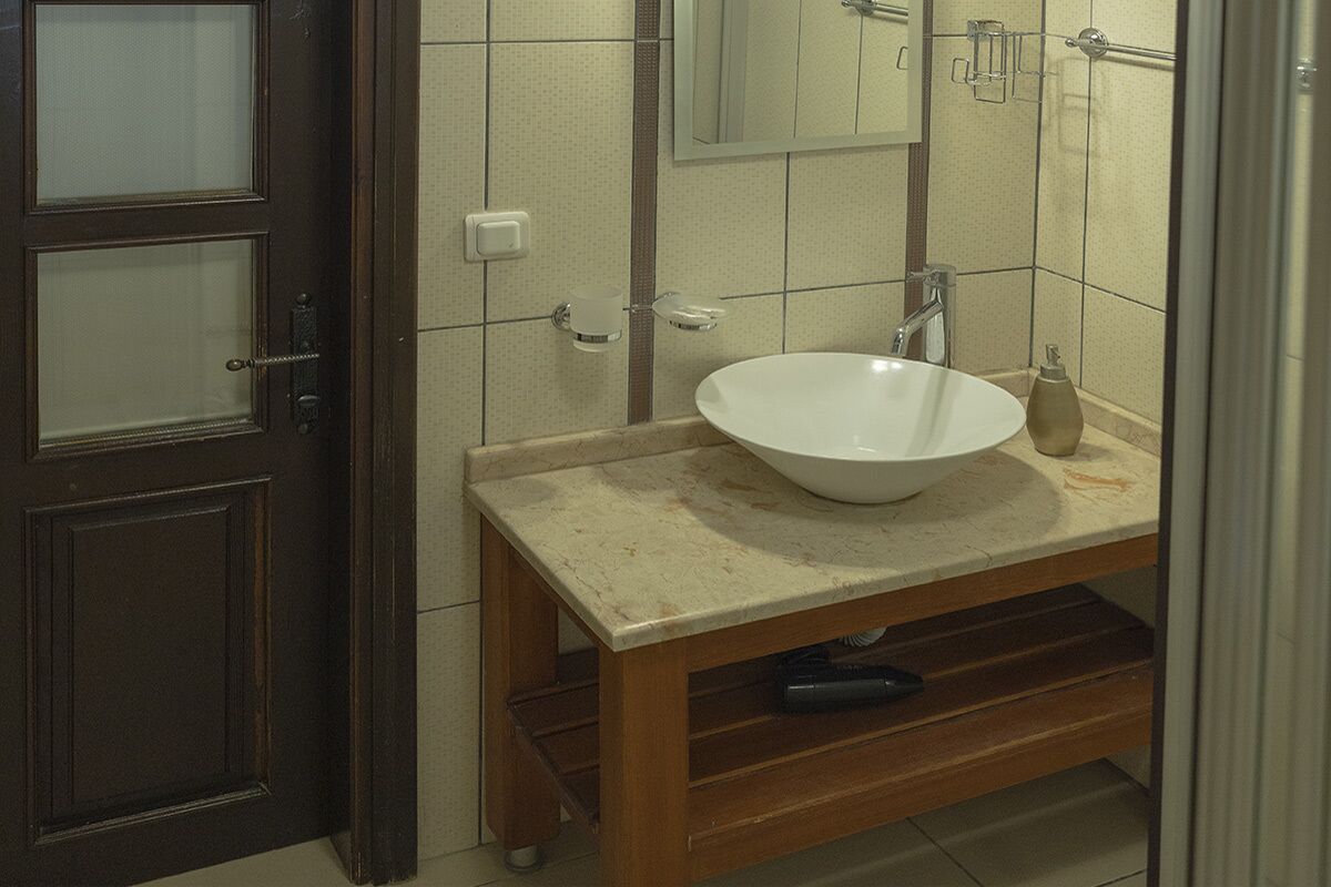 A bathroom with a wooden vanity, a white sink, and a mirror above it.