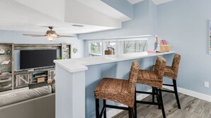 Une cuisine moderne avec un coin bar, une table à manger et des chaises en osier.